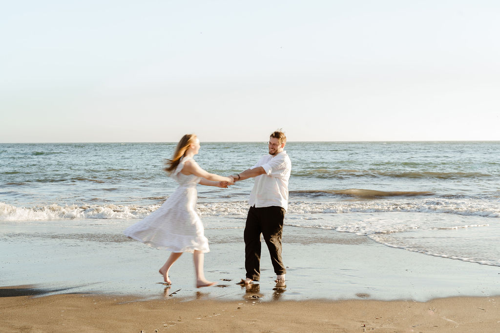 Motion blur of couple twirling around on a california beach at sunset during golden hour for engagement photos