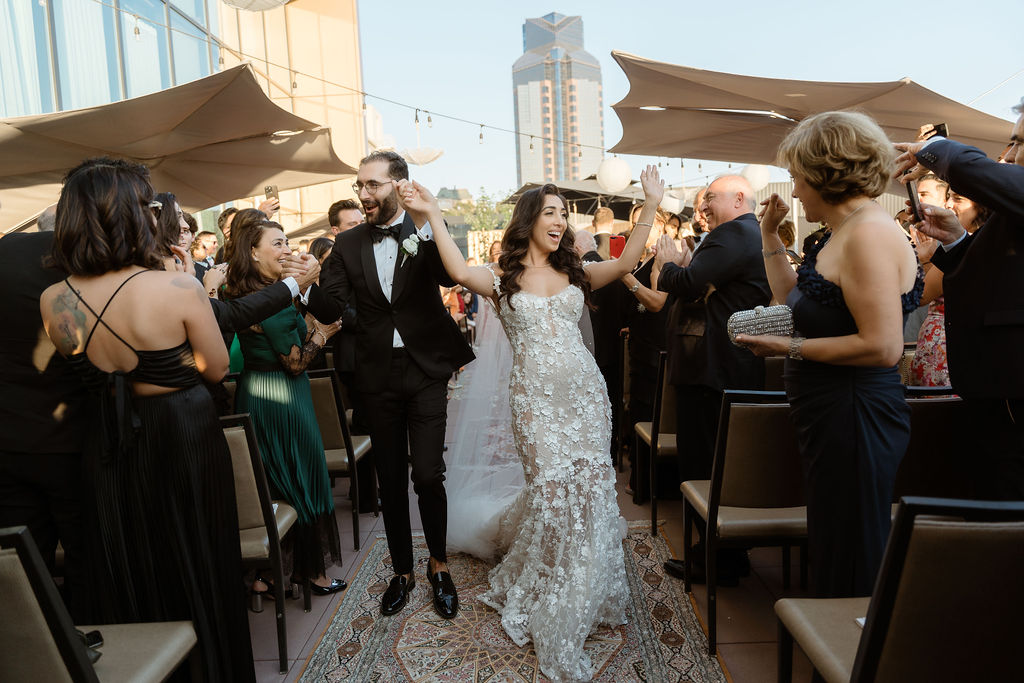 Bride and groom exiting their ceremony walking down the aisle to crowd cheers at Kimpton Sawyer Hotel Wedding