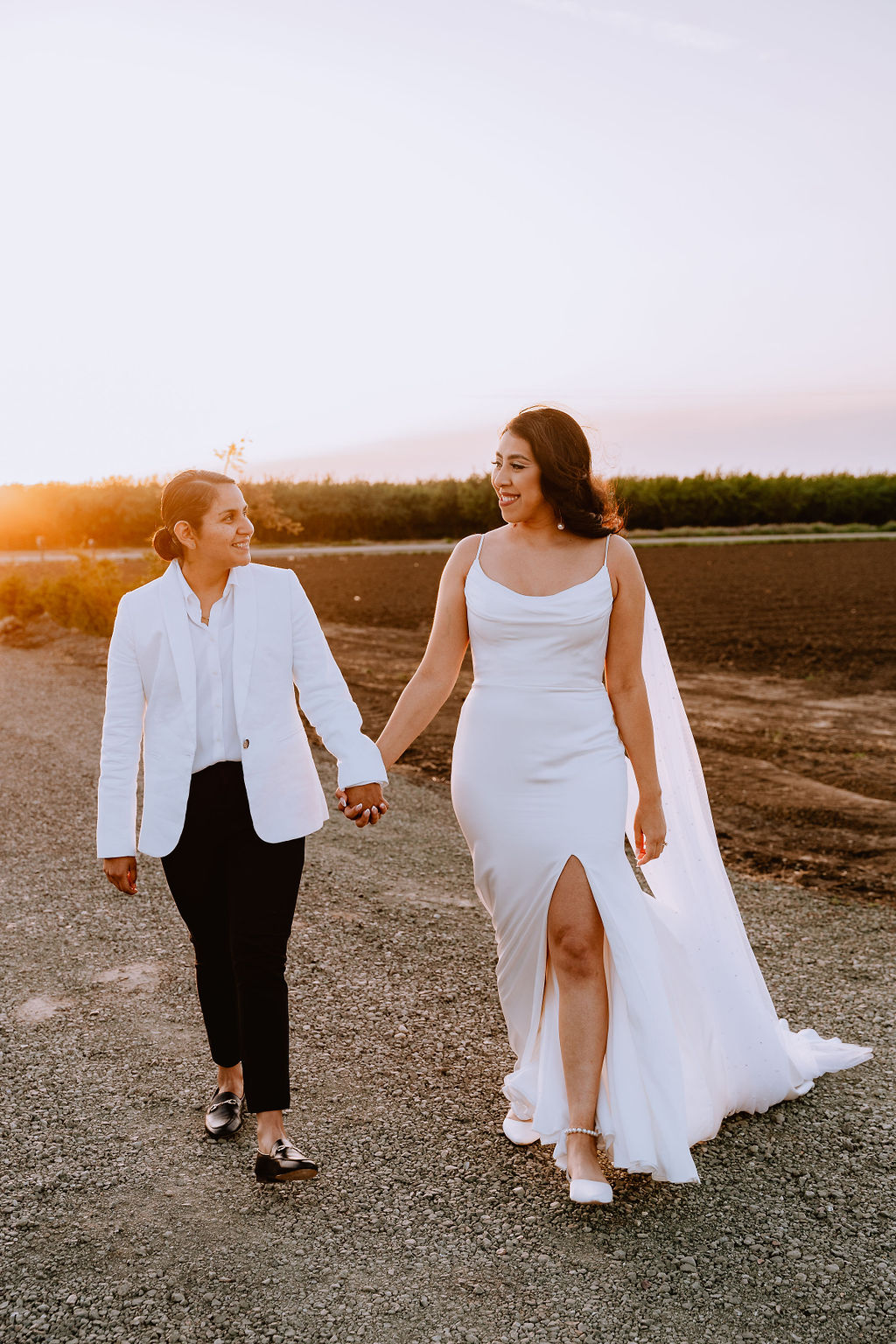 A lesbian couple holding hands and walking together at Bella Vista Farms during golden hour