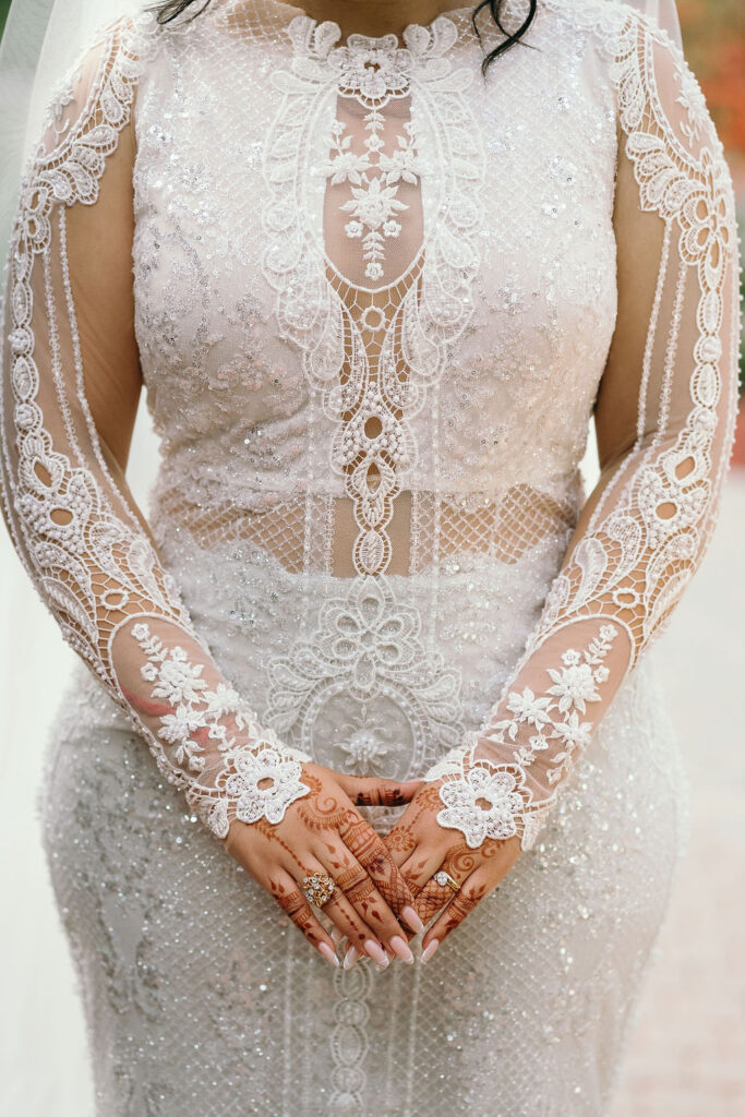 Bride's intricate lace wedding dress with henna-adorned hands at Rancho Las Lomas