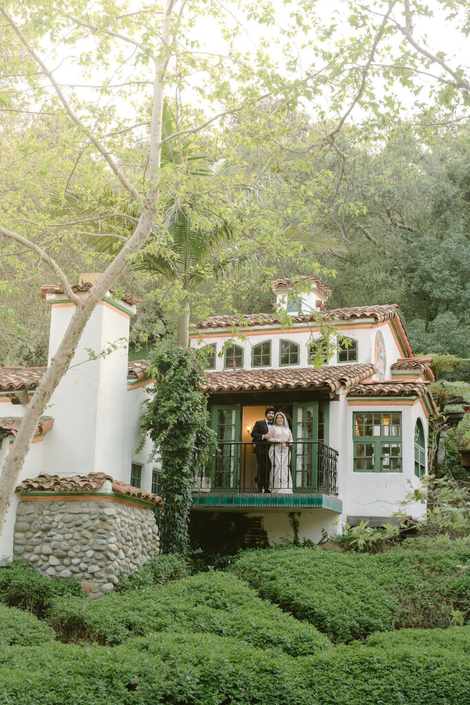 Bride and groom standing on the balcony of a beautiful house at Rancho Las Lomas