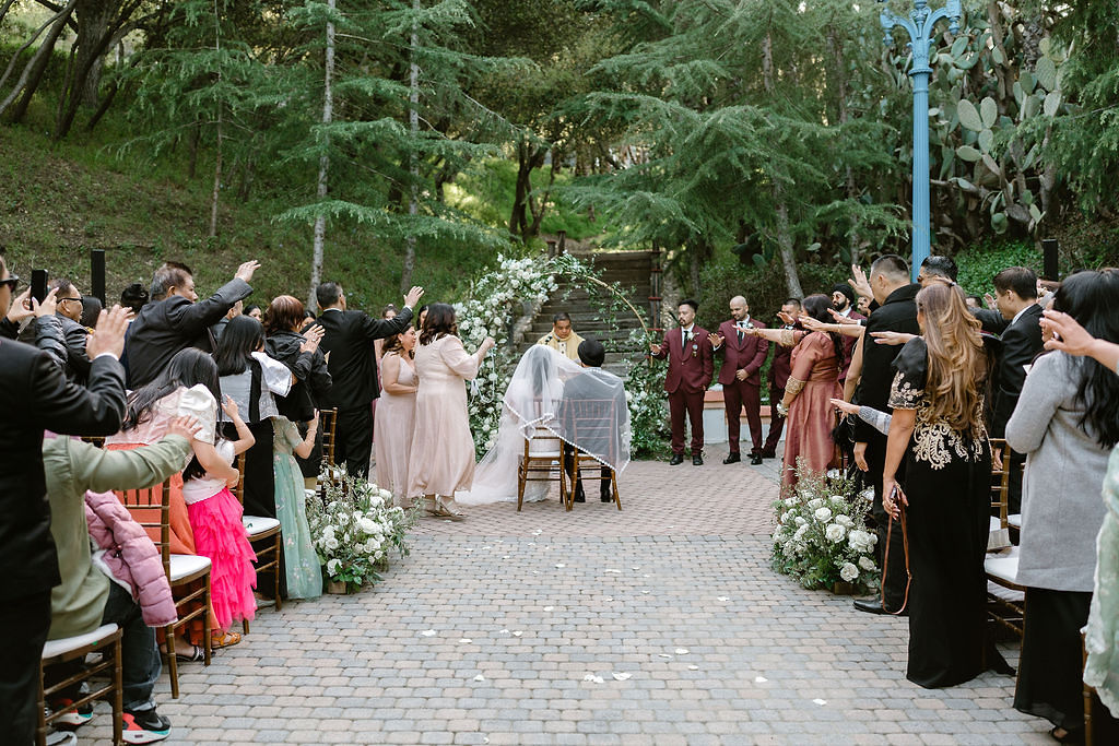 Wedding guests raising hands in blessing at Rancho Las Lomas ceremony.