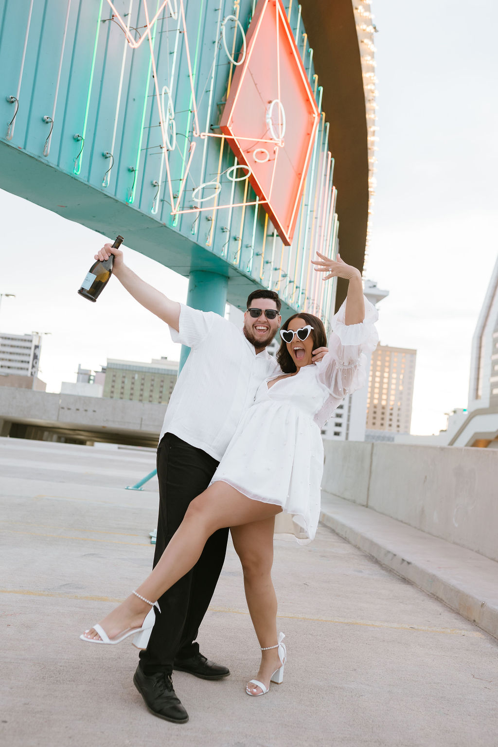 Couple celebrating under neon sign during their engagement photos Las Vegas session