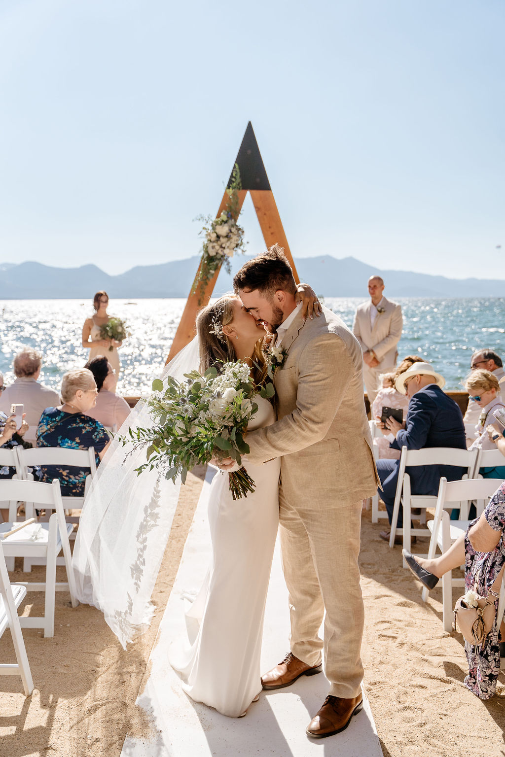 Bride and groom kissing at The Landing Resort and Spa ceremony arch.