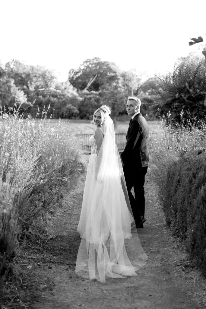 Black and white photo of the bride and groom walking hand-in-hand through a field in Mendocino.