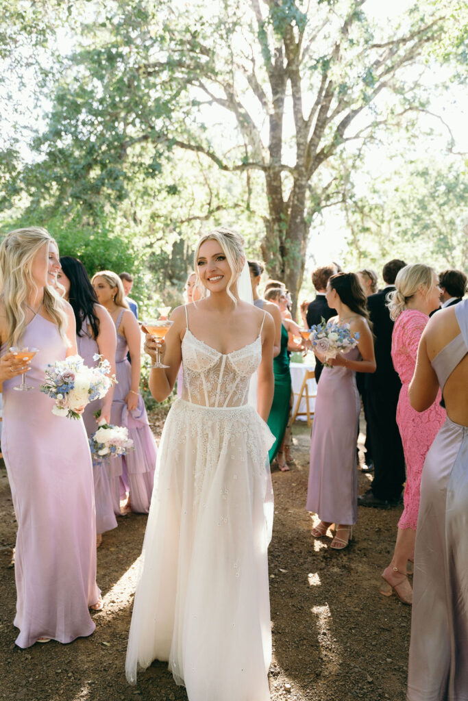 Bride enjoying cocktail hour with bridesmaids in pastel dresses at a Mendocino wedding.