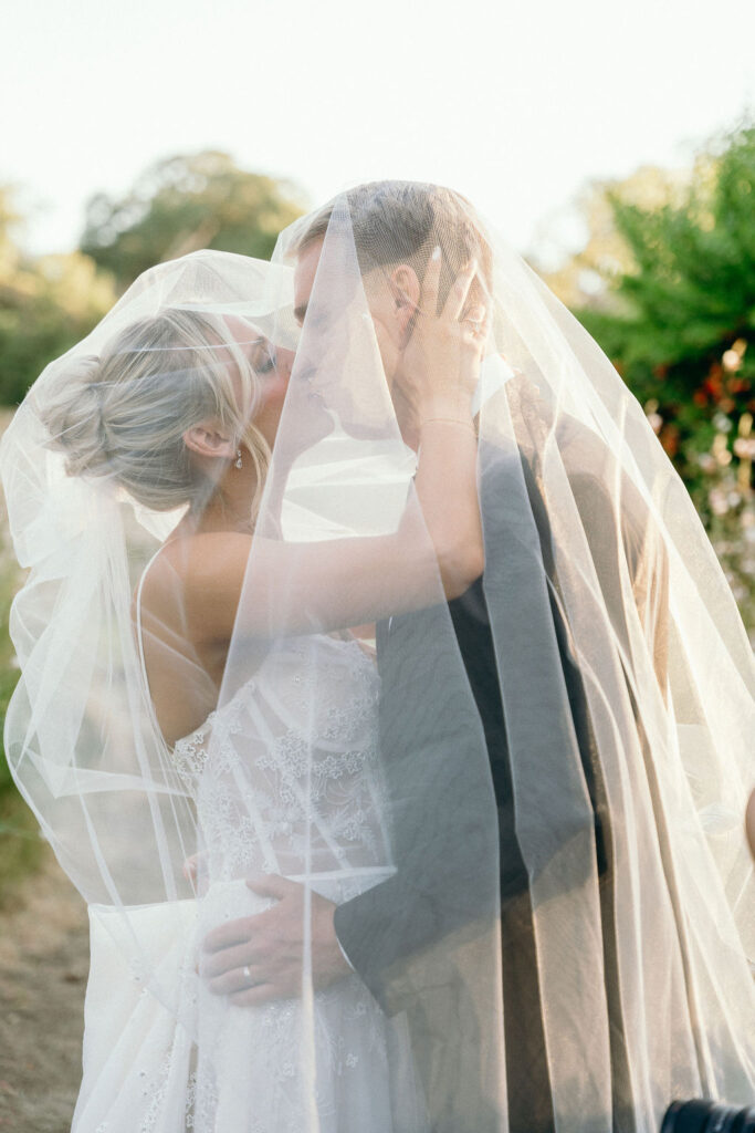  Bride and groom share a kiss under the veil in a garden at a Mendocino wedding