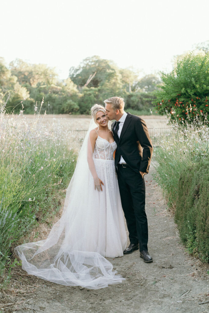 Bride and groom embrace in a field with soft sunlight at a Mendocino wedding