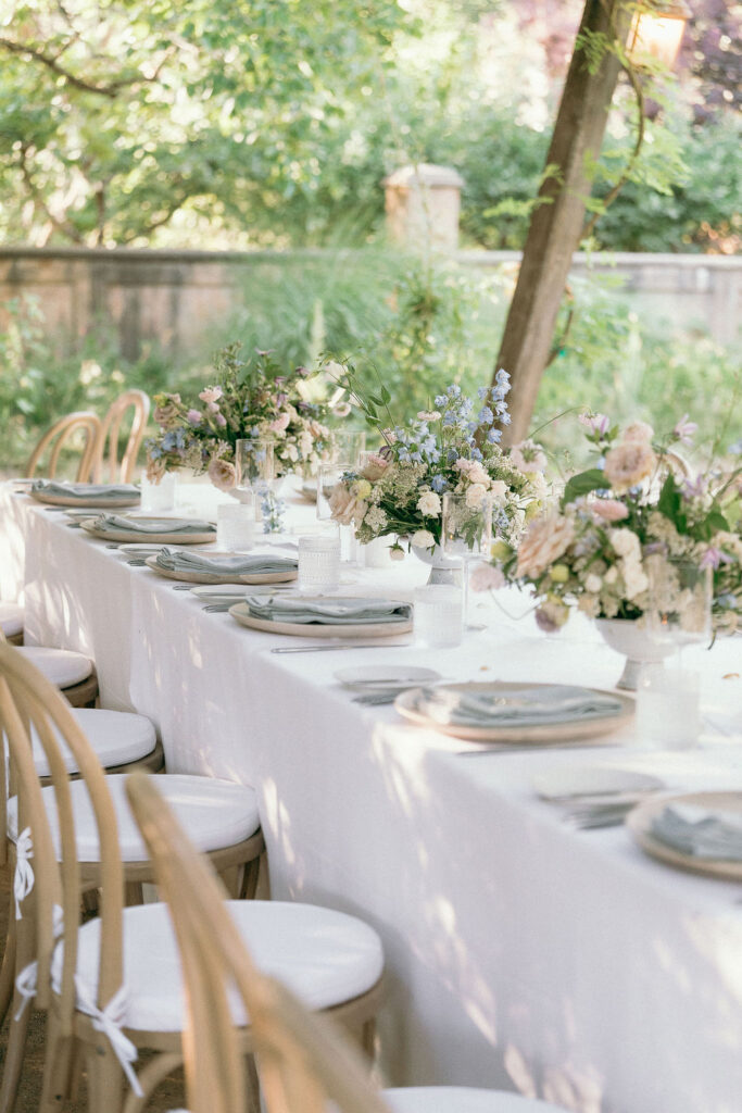 Long banquet table with lush floral arrangements under a pergola at a Mendocino wedding reception.