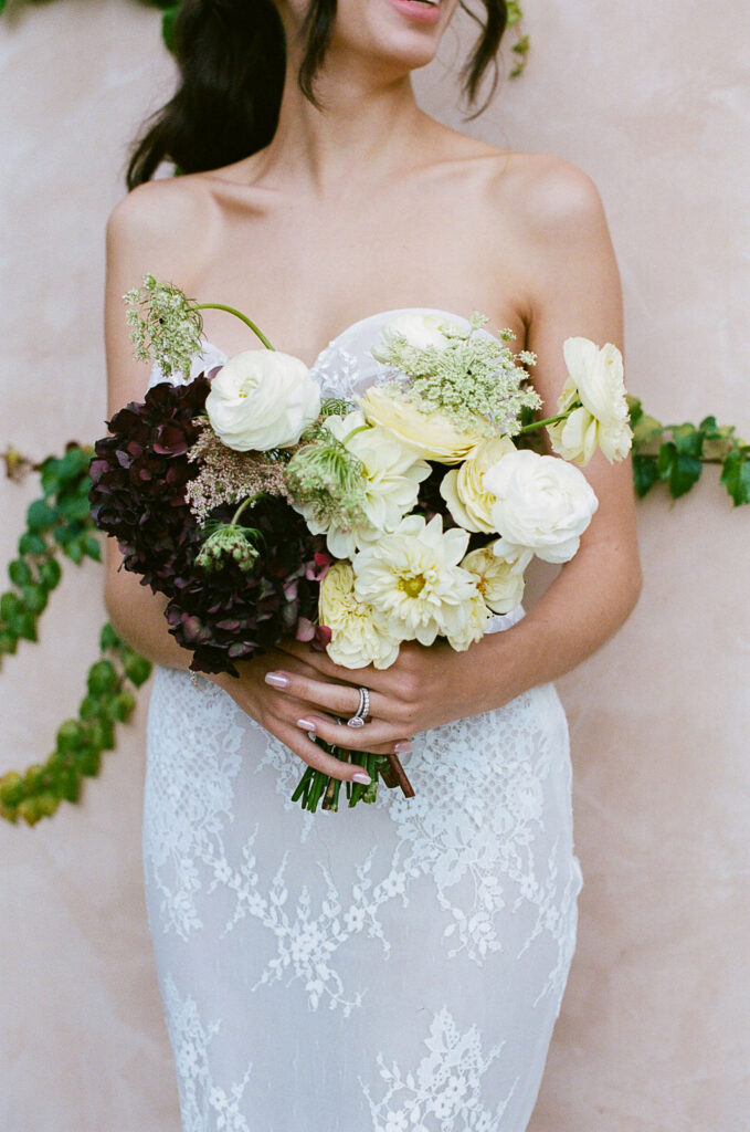 Bride holding a bouquet with white and burgundy flowers at Monserate Winery wedding