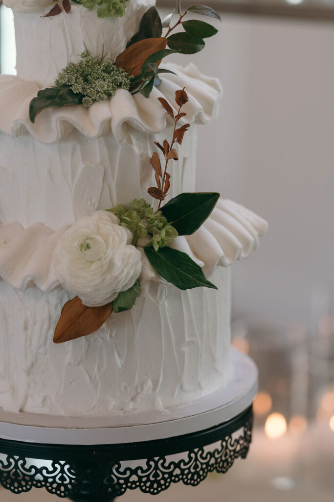 Close-up of a three-tier wedding cake with floral accents at Monserate Winery wedding reception