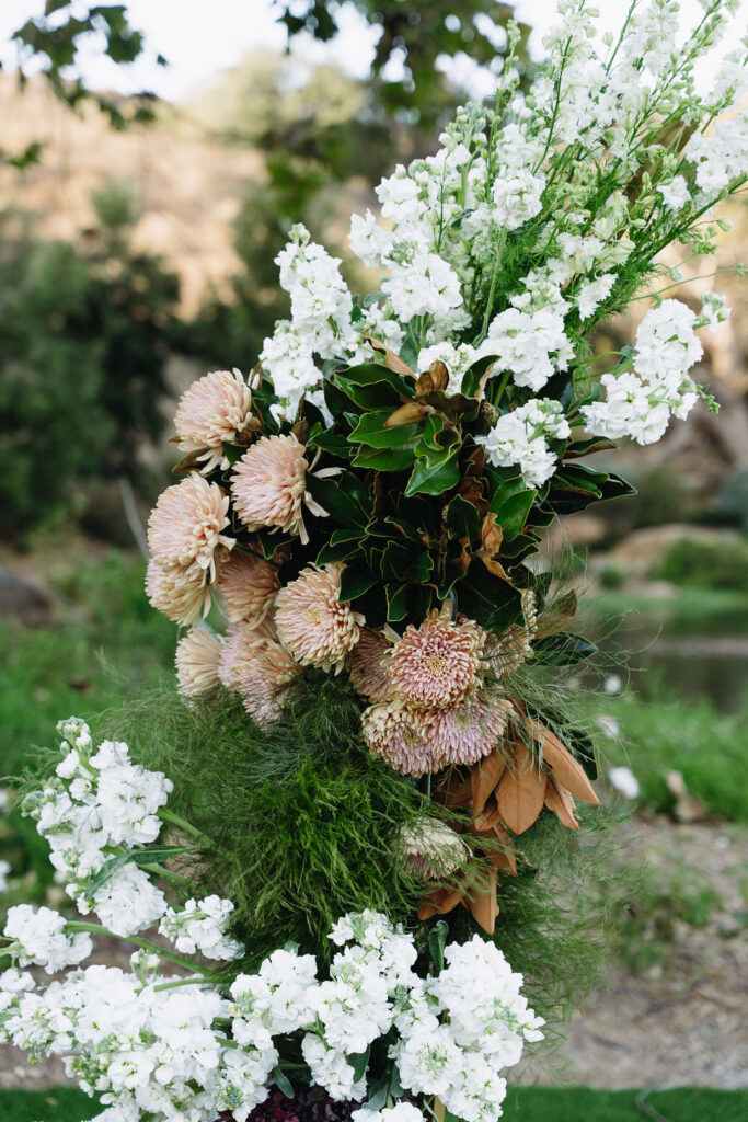 Floral arrangement of white and blush blooms with greenery at outdoor ceremony space at Monserate Winery.