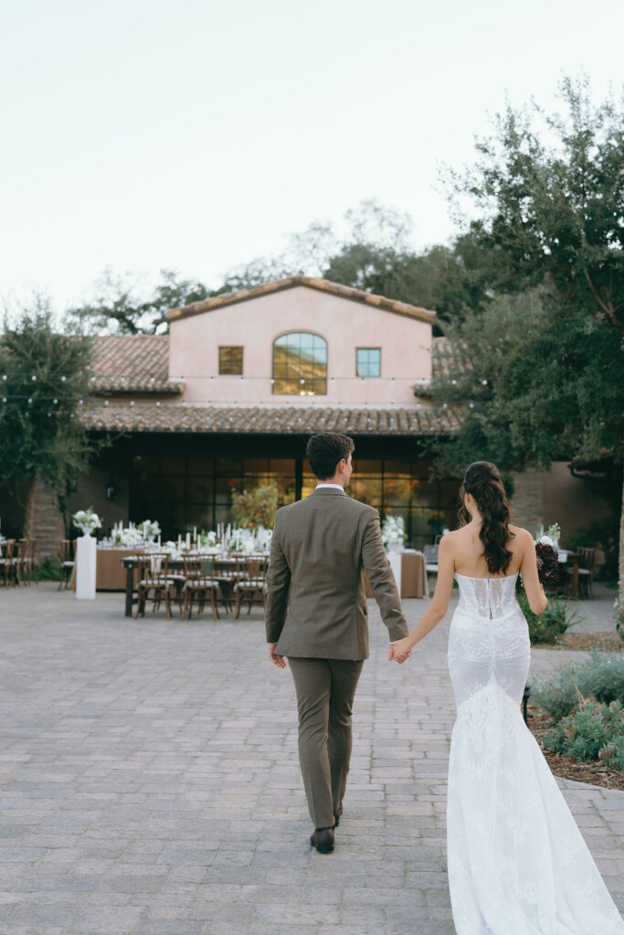 Bride and groom walking toward the reception at Villa De Fiore, Monserate Winery, in elegant wedding attire.