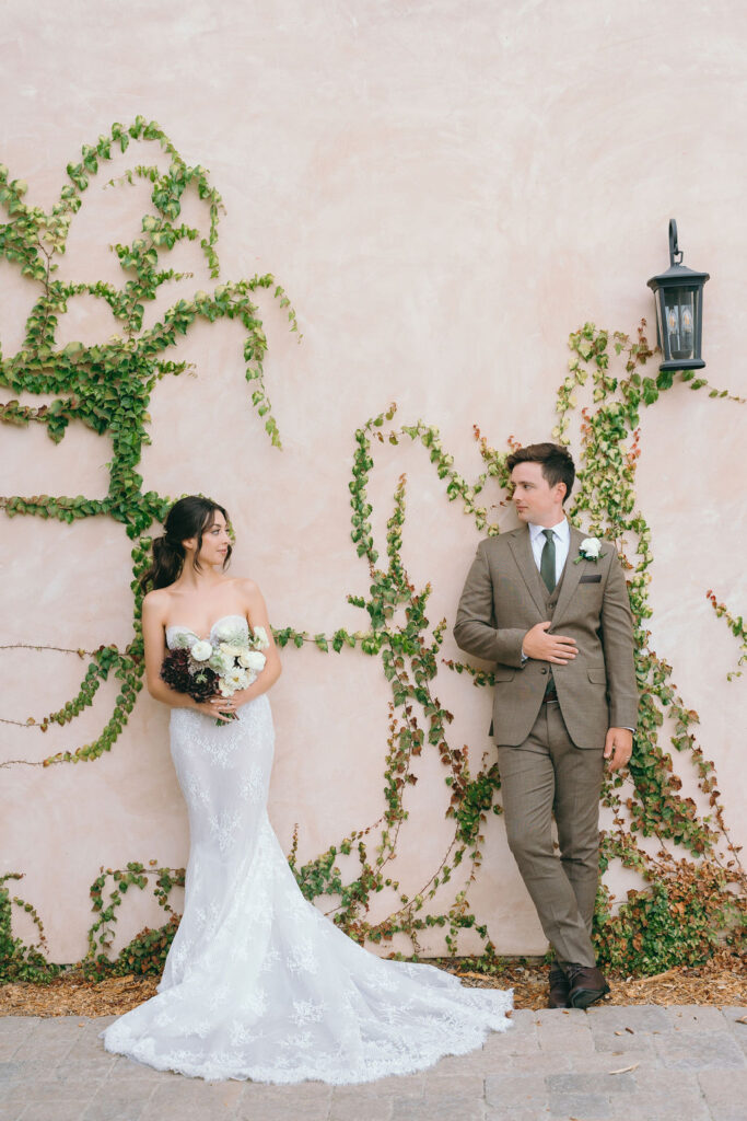 Bride and groom standing against an ivy-covered wall at Villa De Fiore, Monserate Winery.