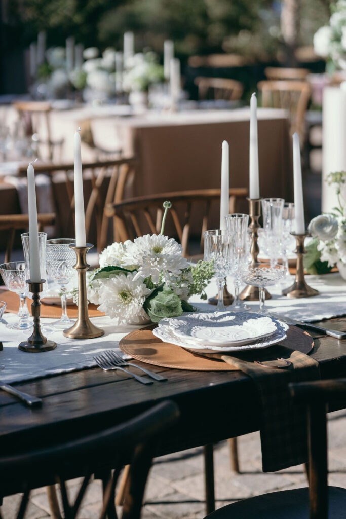 Close-up of wedding table design with brass candleholders, white florals, and crystal glassware at Monserate Winery