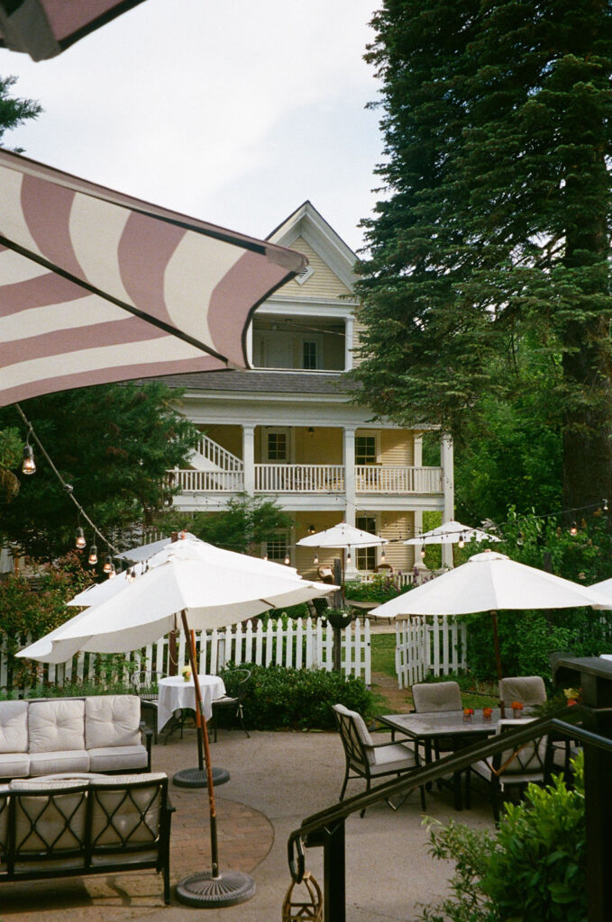 The outdoor patio of McCloud Hotel with white umbrellas and string lights. A charming Northern California wedding venue captured on film. captured by a Northern California Wedding Photographer