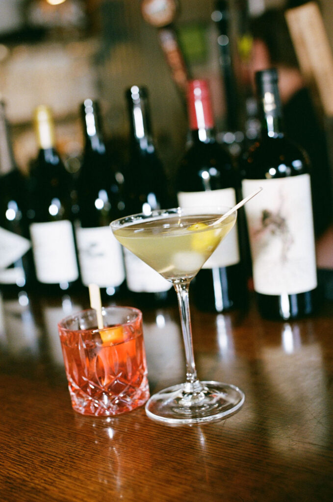 His and hers drink at a wedding reception in front of wine bottles captured by a Northern California Wedding Photographer