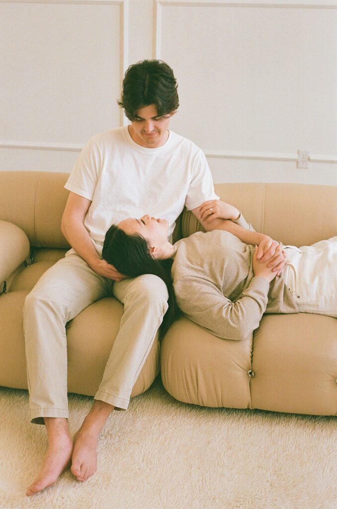 Woman resting on her partner’s lap on a beige couch, taken on 35mm film in a DTLA studio setting.