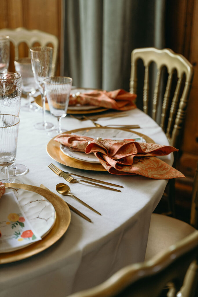 Table setting with gold flatware, textured glassware, and floral-themed napkins at a wedding reception captured by a Northern California Wedding Photographer