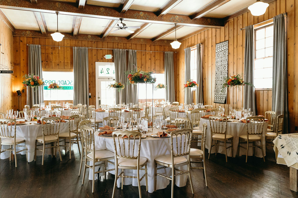 Rustic wedding reception with gold chairs, floral centerpieces, and warm wooden interior captured by a Northern California Wedding Photographer