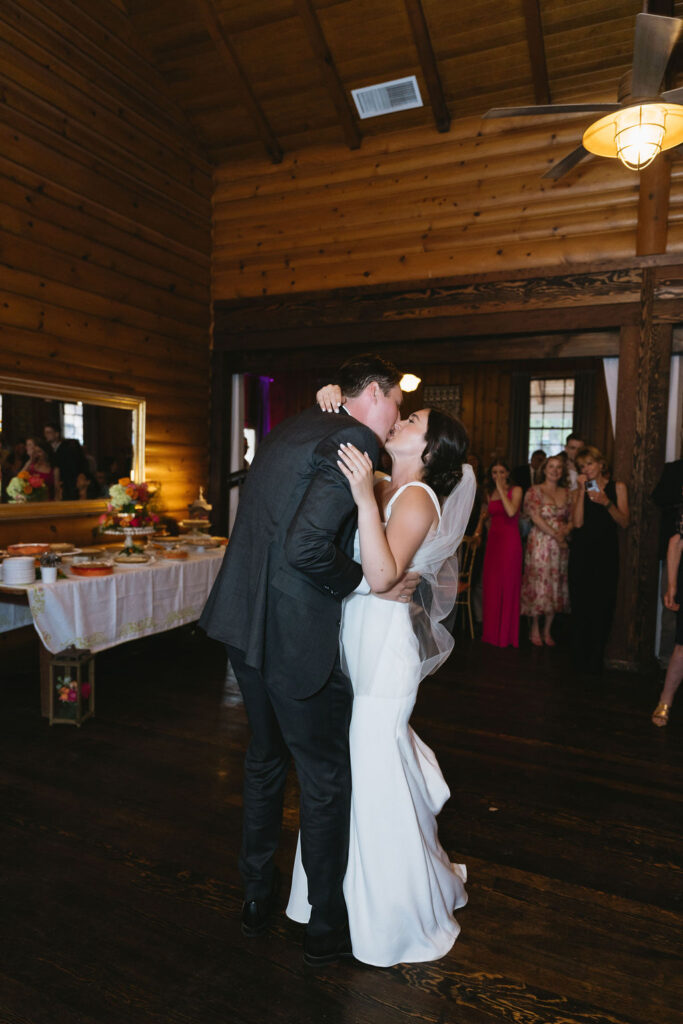 Newlyweds share a final dance, surrounded by friends and family in the reception space.