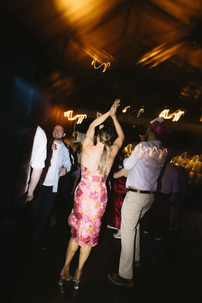 Wedding guest dances under moody lighting, motion blur capturing the energy of the night.