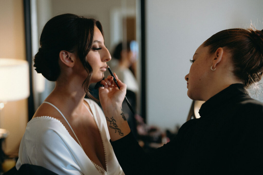 Close up of a bride getting her lip stick touch up by makeup artist during getting ready