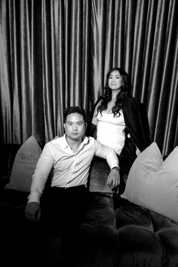 Black and white engagement portrait of a couple at a San Diego lounge with a velvet curtain backdrop