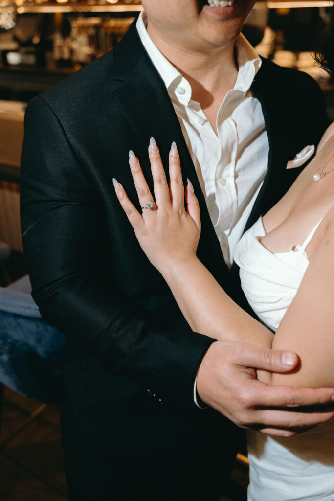 Close-up of an engagement ring on the bride-to-be’s hand as she embraces her fiancé at a San Diego bar.