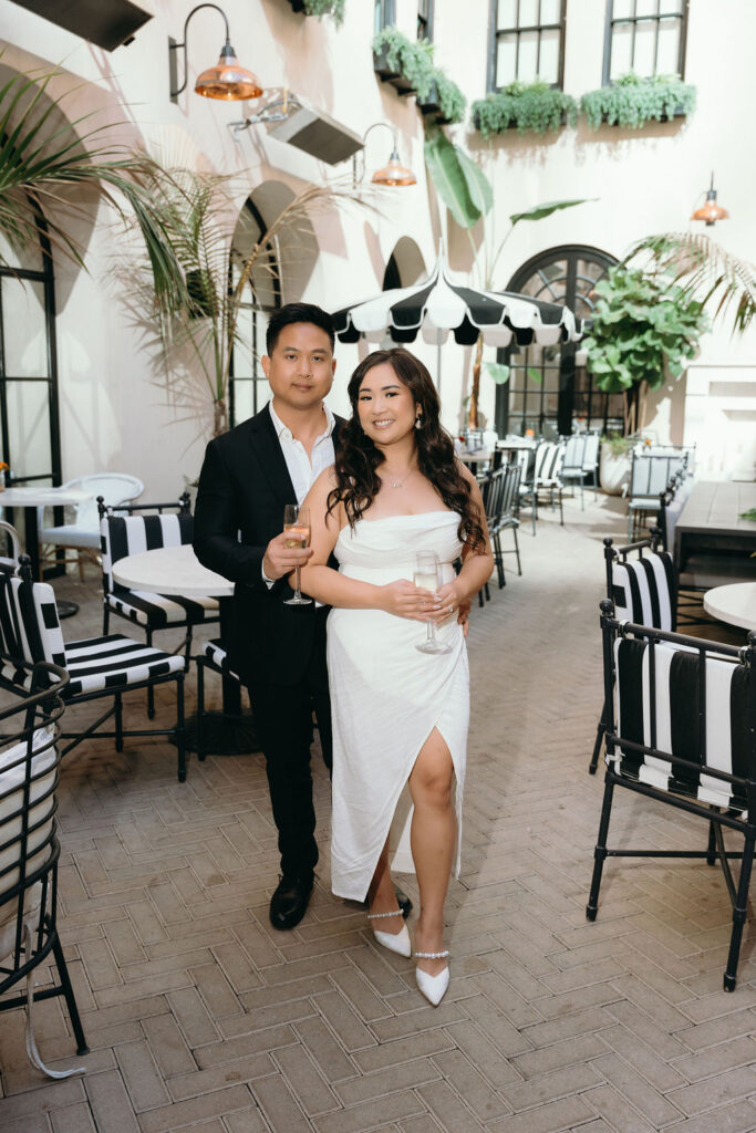 An intimate moment of ViLan and Jason toasting champagne at The Guild Hotel during their bar engagement sessio