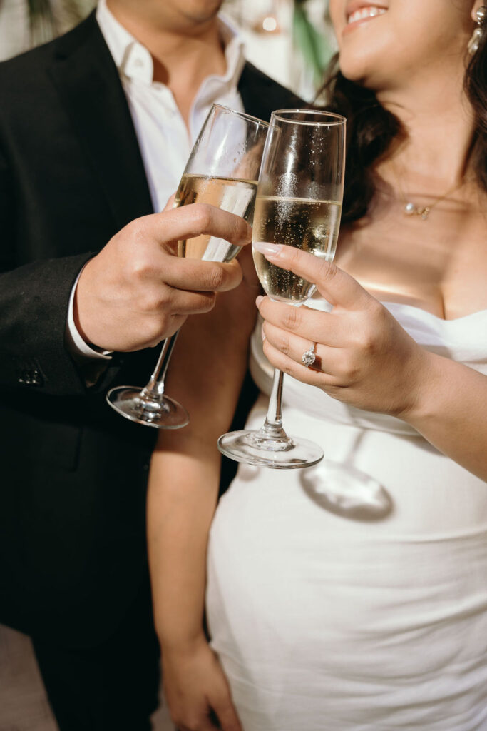 Couple toasting champagne flutes during their engagement session at an upscale San Diego venue.