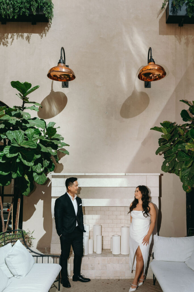 ViLan and Jason pose against sunlit archways and tropical plants, adding a sophisticated touch to their engagement session.