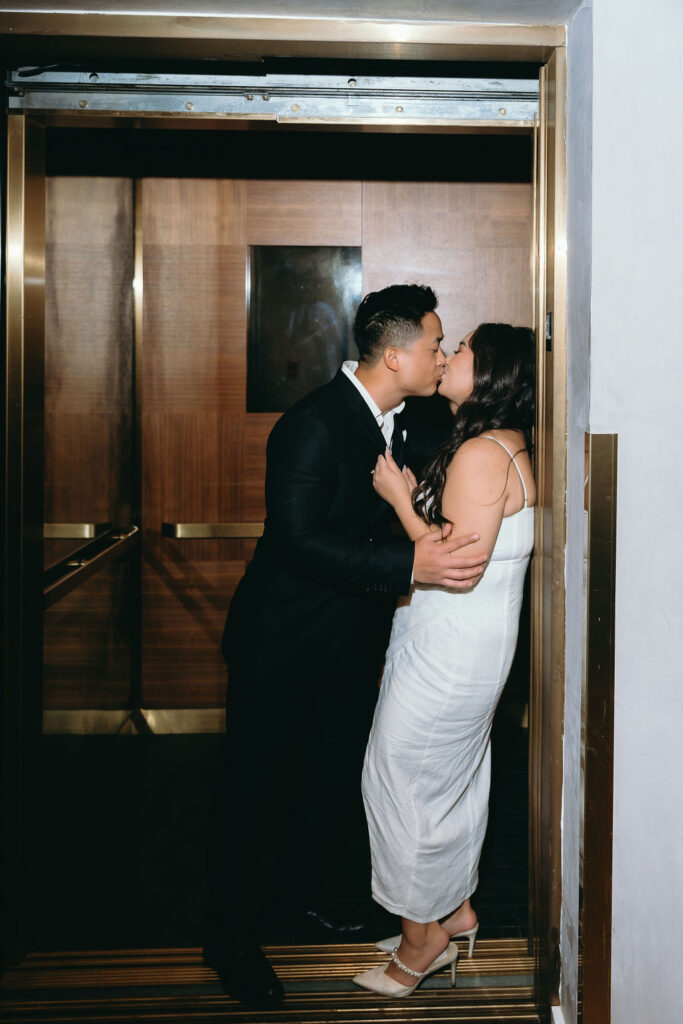 Romantic elevator kiss between engaged couple at a luxury San Diego hotel during their engagement session