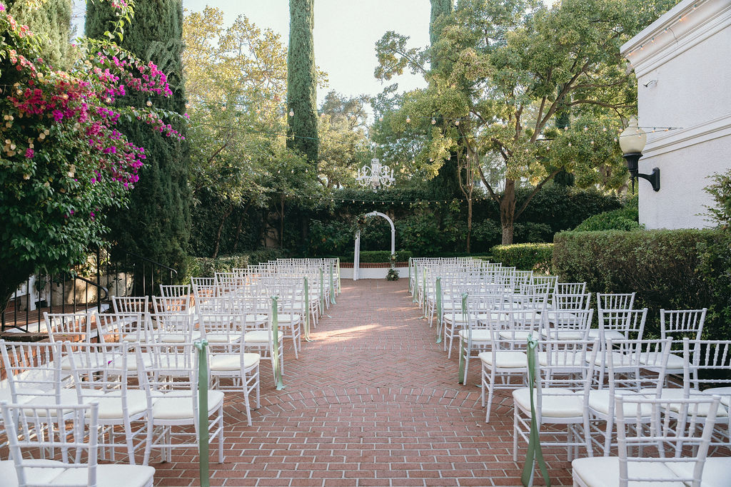 Outdoor wedding ceremony setup at Vizcaya Sacramento with white chairs, a brick aisle, and lush greenery