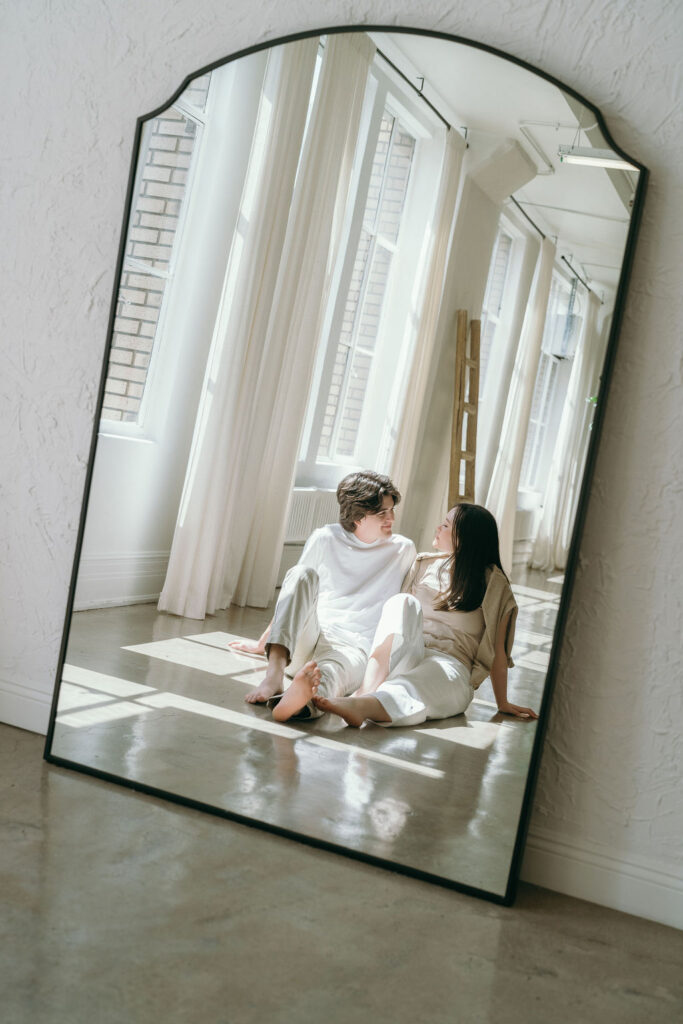 Couple standing and laughing in front of a mirror in a bright, modern DTLA studio.