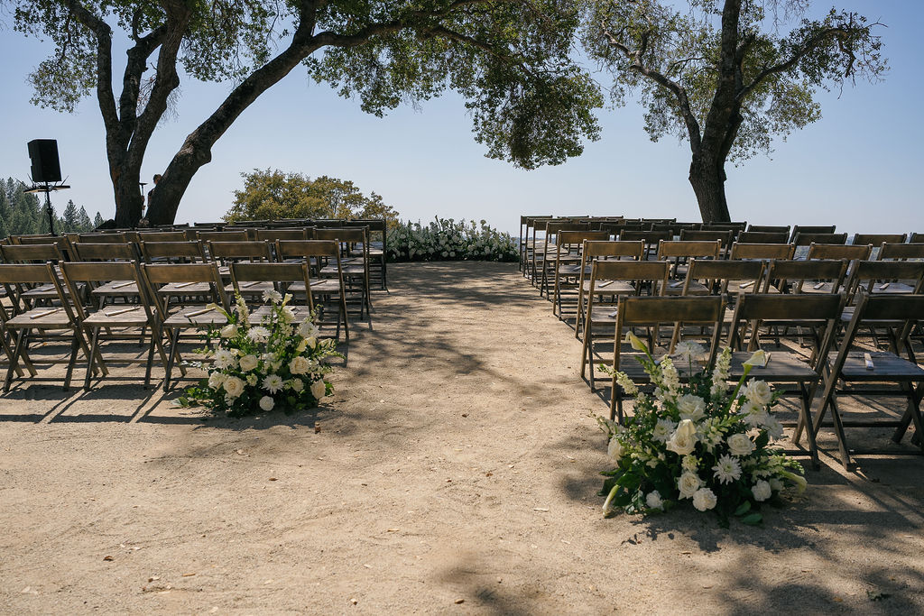 Ceremony chairs and floral aisle arrangements set under oak trees at Black Oak Mountain Vineyards.