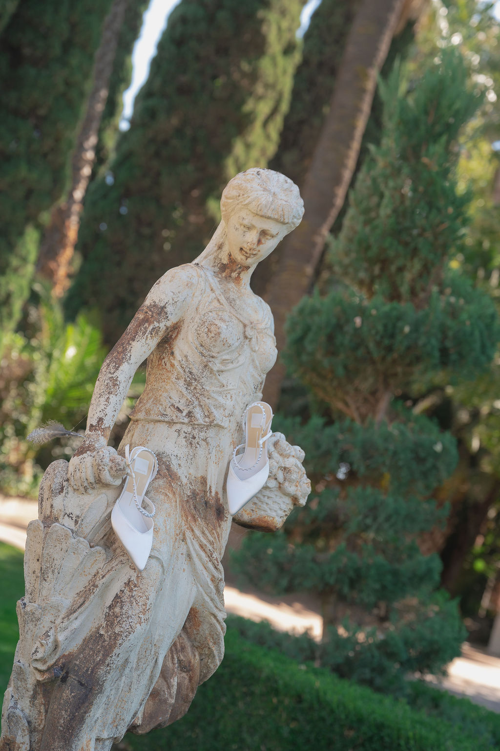 Bridal shoes displayed on a stone statue at Grand Island Mansion garden.