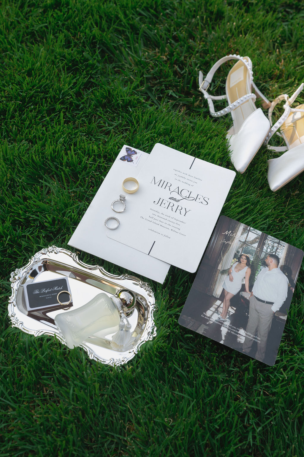 Wedding flat lay at Grand Island Mansion with invitation, rings, shoes, and silver tray.