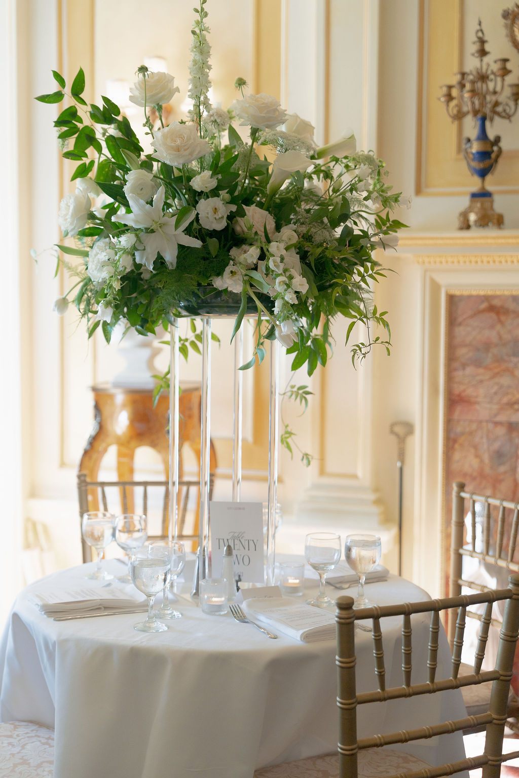 Tall centerpiece of white flowers and greenery on dining table at Grand Island Mansion.