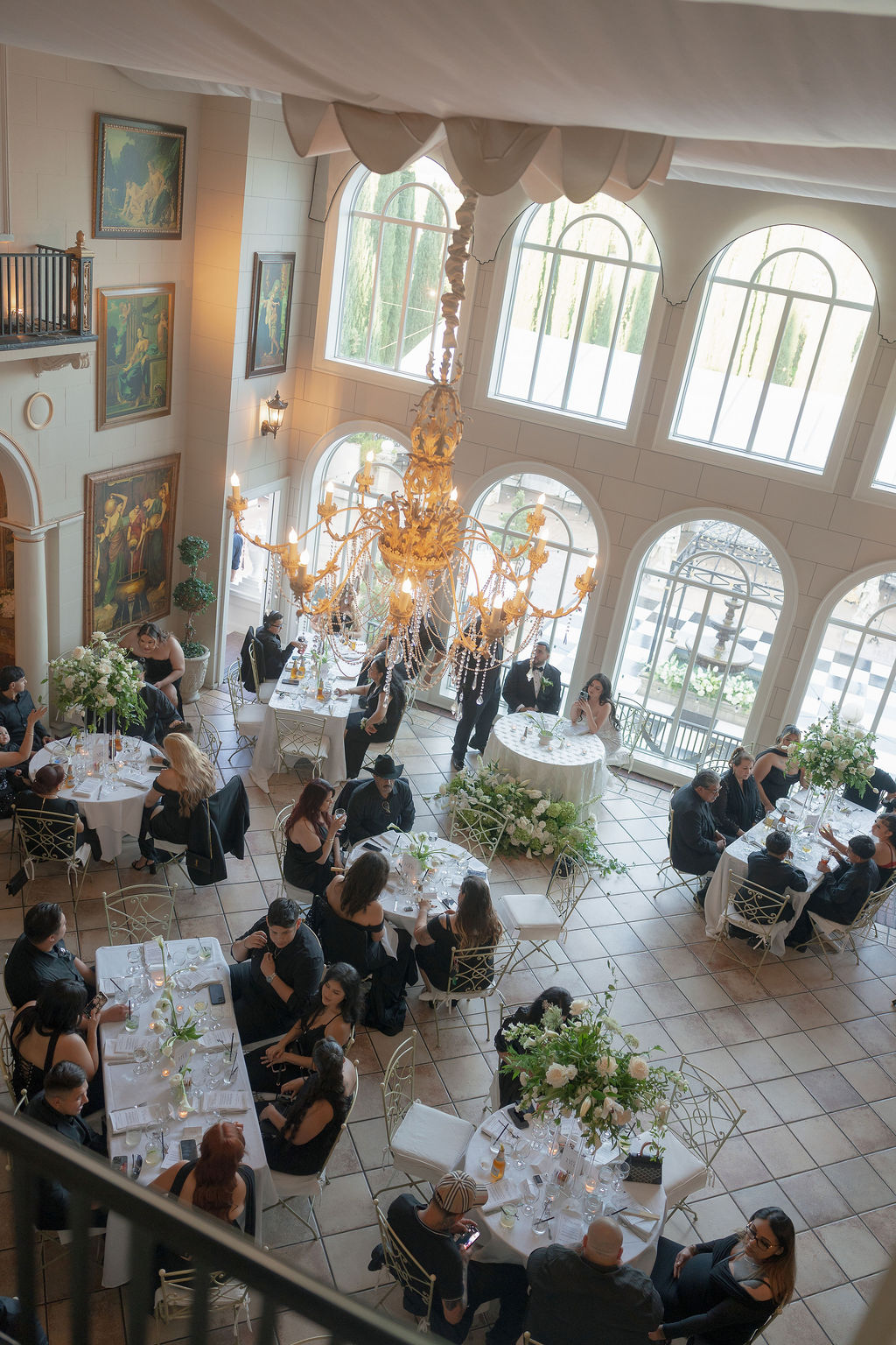 . Guests seated for dinner under chandelier inside Grand Island Mansion.