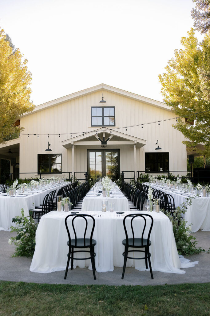 Long banquet tables styled with black chairs and romantic white linens at Park Winters Wedding reception.