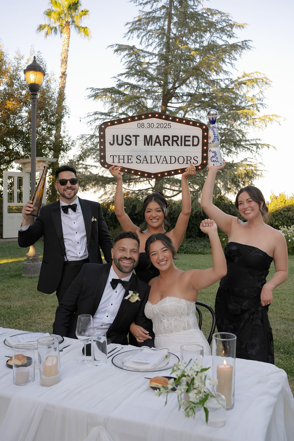 Bride and groom at sweetheart table with friends holding a "Just Married" sign at Park Winters Wedding