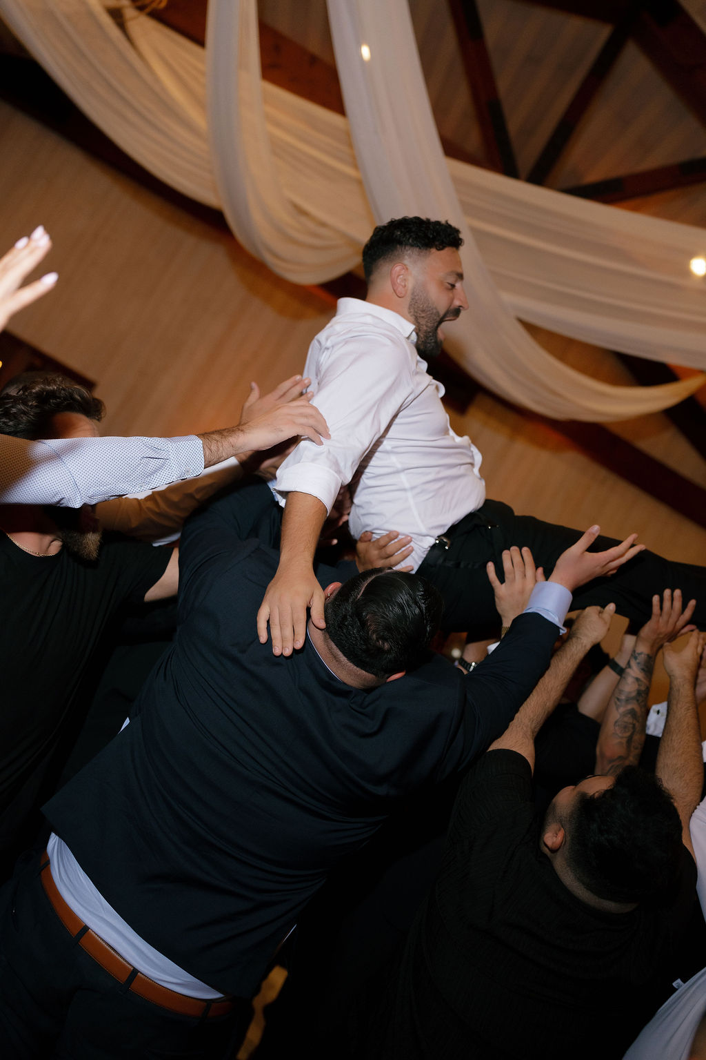 Groom lifted into the air by guests during lively reception at Park Winters Wedding