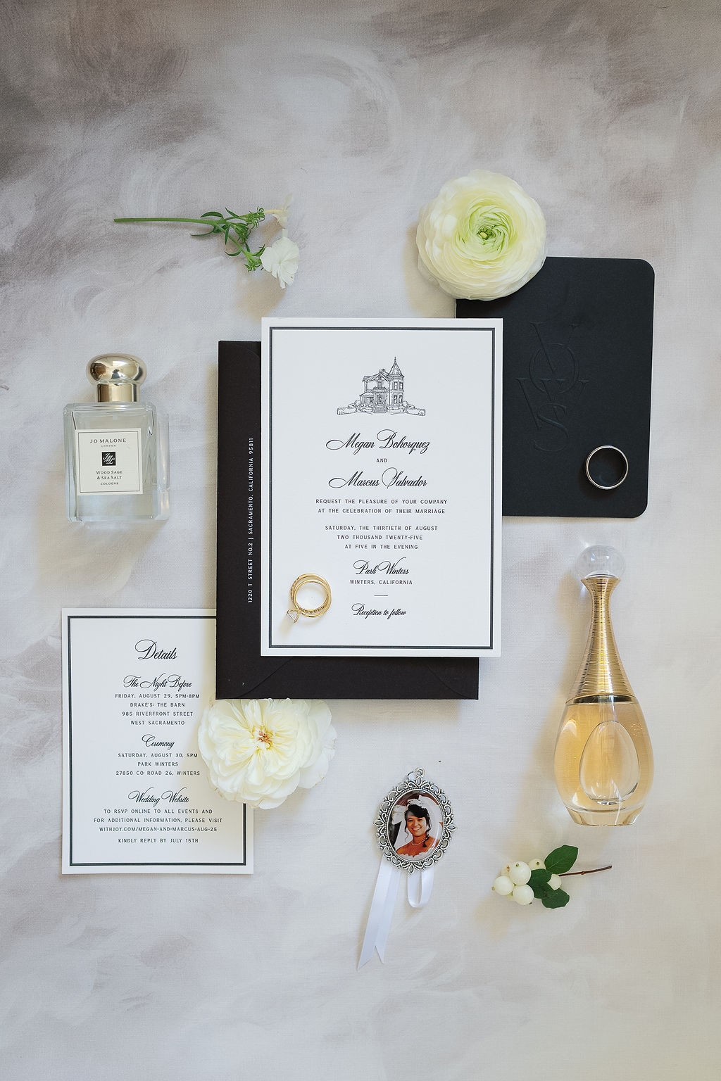 Flat lay of Park Winters wedding invitations with rings, perfume, and floral