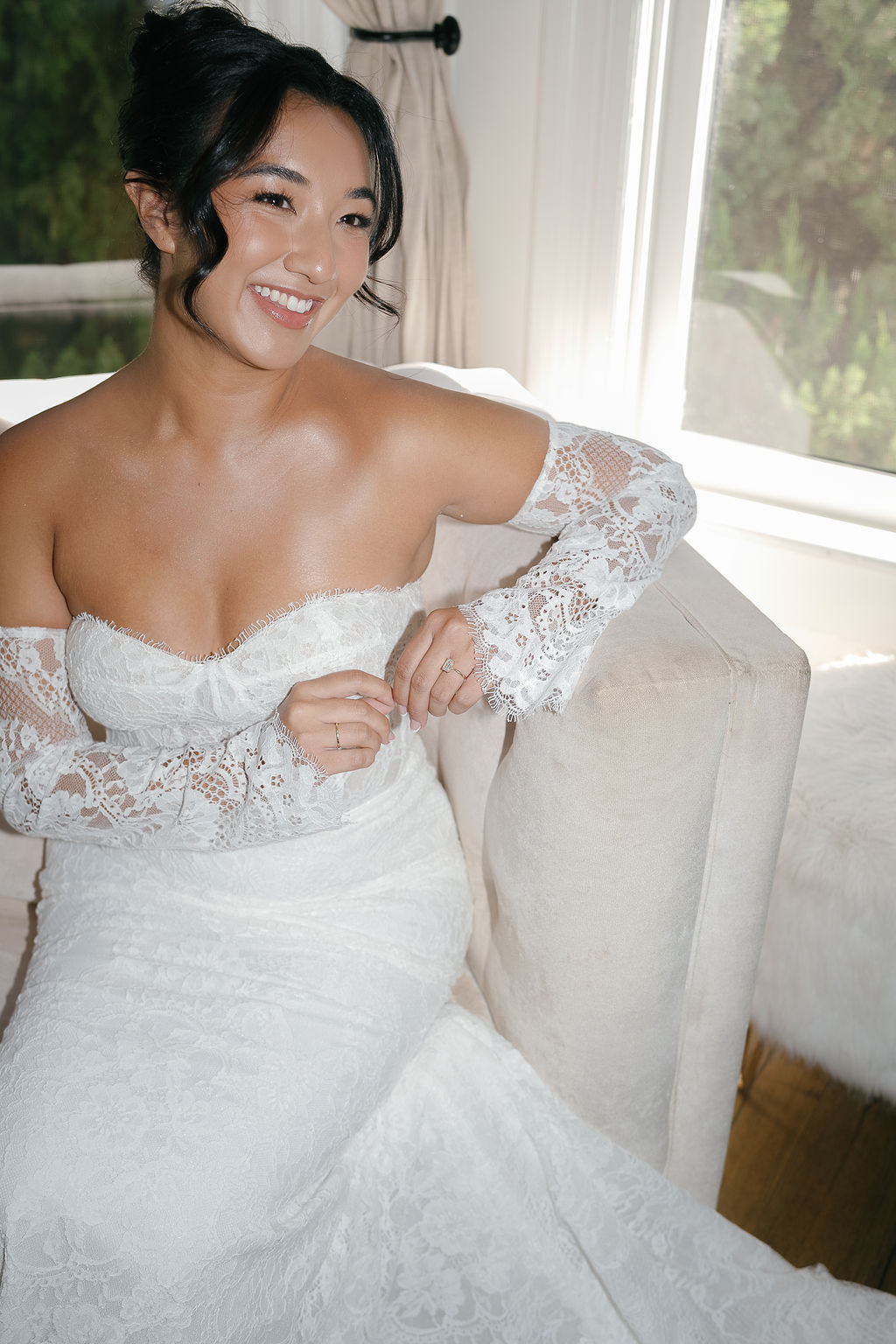 Bride in lace gown sitting indoors, smiling before Park Winters wedding ceremony